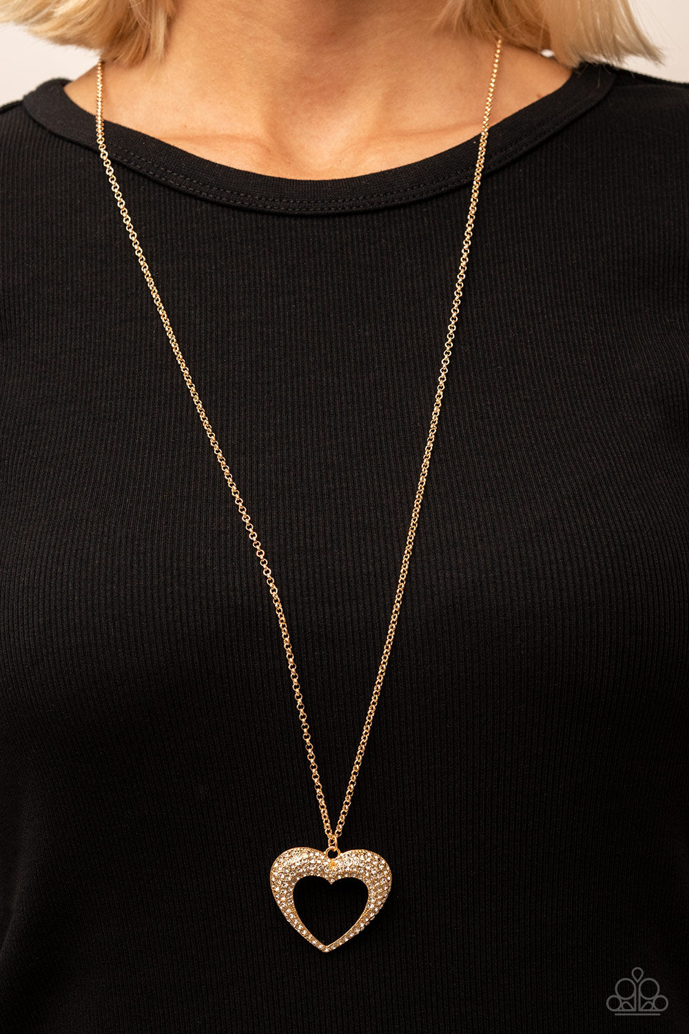 long gold heart necklace. The heart is covered with rhinestones