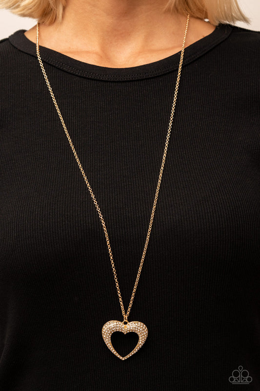 long gold heart necklace. The heart is covered with rhinestones